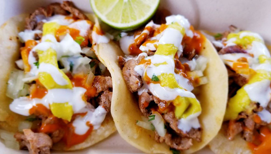 close up image of three fish tacos with a lime wedge